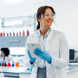 Woman in a lab coat and safety gear engaged during Lab Safety Awareness Week