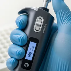 A close-up of a gloved hand holding a sleek, modern electronic pipette.