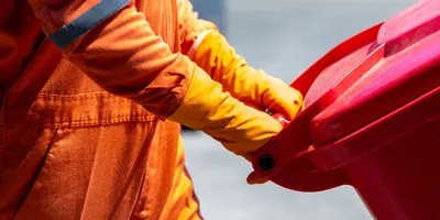 Worker in protective gear handling hazardous waste container