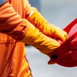 Worker in protective gear handling hazardous waste container