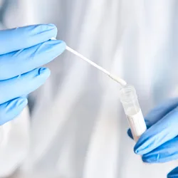 Close up of laboratory worker's gloved hands holding swab test tube
