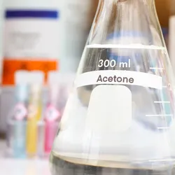 Laboratory acetone in Erlenmeyer flask on lab bench with chemical storage bottles