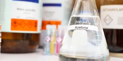 Laboratory acetone in Erlenmeyer flask on lab bench with chemical storage bottles