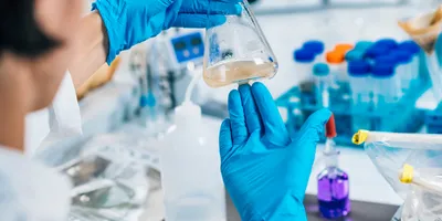 Researcher using a flask for microfluidic pollutant detection.