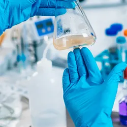 Researcher using a flask for microfluidic pollutant detection.
