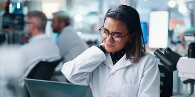 Laboratory worker experiencing shoulder discomfort, highlighting RSI risks