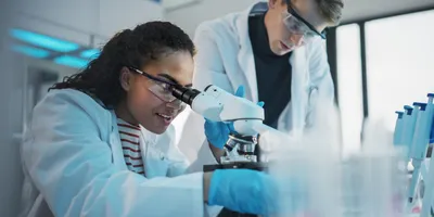 Biologists examining samples with a microscope in a modern lab