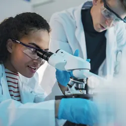 Biologists examining samples with a microscope in a modern lab