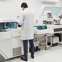Male researcher in a laboratory working, standing next to a machine.