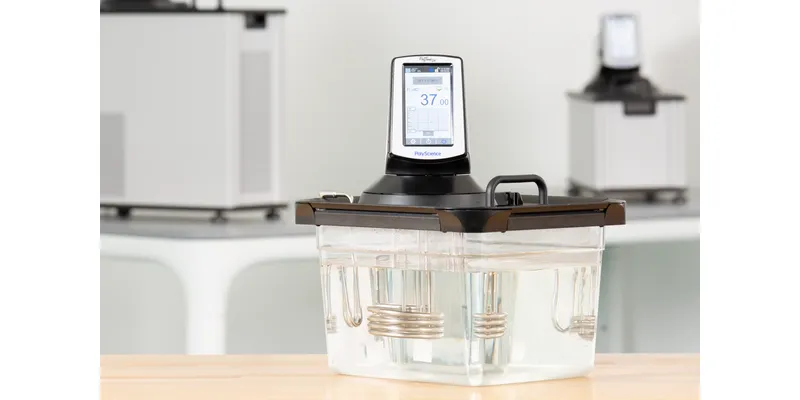 A PolyScience immersion circulator mounted on a clear water bath tank.