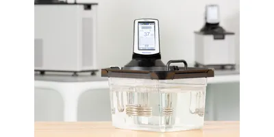 A PolyScience immersion circulator mounted on a clear water bath tank.