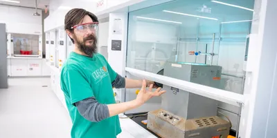 Researcher demonstrating lab equipment in the Advanced Materials Innovation Complex