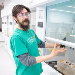 Researcher demonstrating lab equipment in the Advanced Materials Innovation Complex