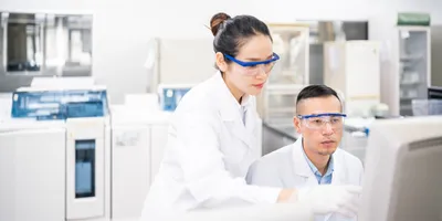 Two scientists looking at computer in lab, attempting to make decisions