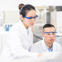 Two scientists looking at computer in lab, attempting to make decisions