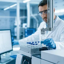 Analytical chemist in modern lab loading sample vial into automated headspace gas chromatograph.