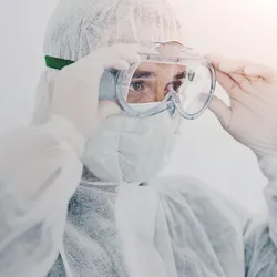 Worker adjusting PPE goggles for safety compliance
