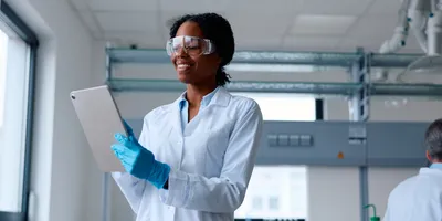 Professional in lab coat using a tablet to enhance workplace safety trends.