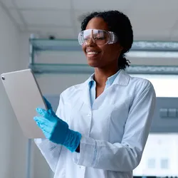 Professional in lab coat using a tablet to enhance workplace safety trends.