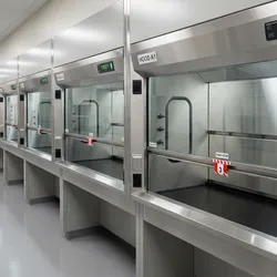 A photorealistic laboratory corridor showing a row of modern fume hoods with sashes closed at the minimum working height, sash stop markers clearly visible.