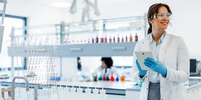 Scientist wearing a lab coat and gloves is using a digital tablet in a modern laboratory