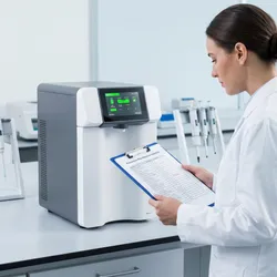 A laboratory technician in a white lab coat reviewing a printed preventive maintenance schedule on a clipboard, standing in front of a modern benchtop ultrapure water purification system.