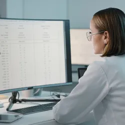 Scientist reviewing lab data on a computer monitor.