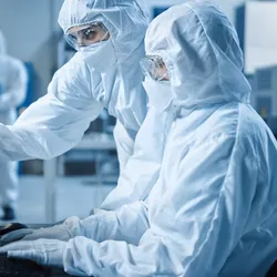 Laboratory staff in white suits focusing on biosafety and biocontainment practices.