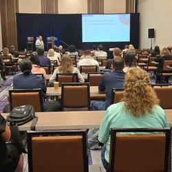 View of the back of a conference room filled with attendees listening to a Leadership Summit presentation.