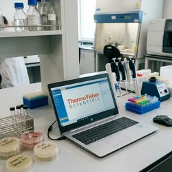 open laptop displaying Thermo Fisher Scientific logo on a laboratory bench in a modern microbiology lab