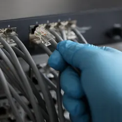 Technician connecting lab equipment with network cables.