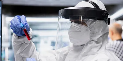 Laboratory technician wearing personal protective equipment while handling a sample.