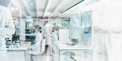 View of busy research laboratory with multiple scientists walking through and working
