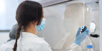 Woman Scientist with long brown hair working in a biosafety cabinet