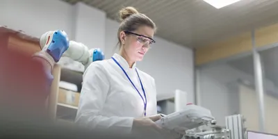 Woman in lab focusing on robotic automation equipment