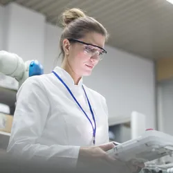 Woman in lab focusing on robotic automation equipment