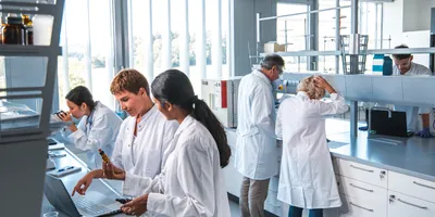 Team of five researchers conducting various tasks within the lab, with laboratory ventilation equipment seen on the ceiling.