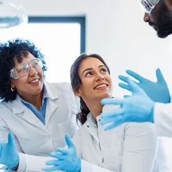 Three scientists in a laboratory discuss results.