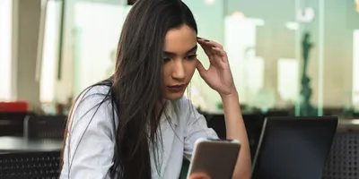 Job seeker looking concerned while using a smartphone during the hiring process.