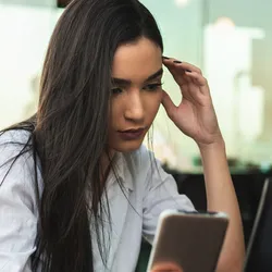 Job seeker looking concerned while using a smartphone during the hiring process.