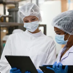 two food scientists looking over data on tablets