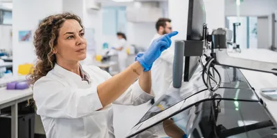 Woman in a lab coat operating equipment in a clinical laboratory.