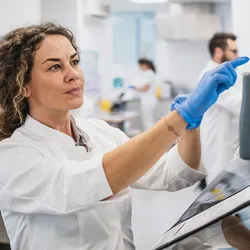 Woman in a lab coat operating equipment in a clinical laboratory.