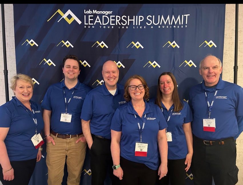 From left: Alyssa Moore, Holden Galusha, Scott Wallask, Cayley Thomas, Lauren Everett, and Scott Hanton pose in front of the Leadership Summit event backdrop.