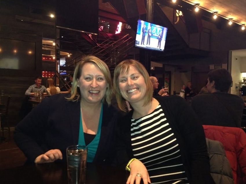 Alyssa Moore and Cayley Thomas smiling for a picture at a restaurant.