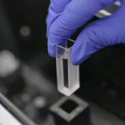 Analyst is loading a sample into a testing machine in a laboratory