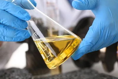 Male hands in protective gloves hold test tube in hands produces chemistry test of motor oil automatic gearbox and hydraulic booster