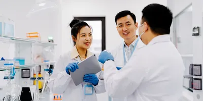 Three lab professionals effectively communicating in the lab.
