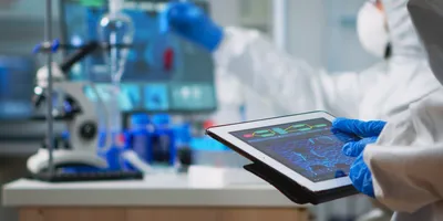 Back view of scientist in coverall analyzing virus evolution looking on digital tablet.