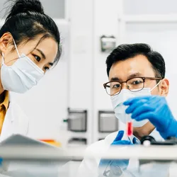 Two Asian scientists working together in lab.